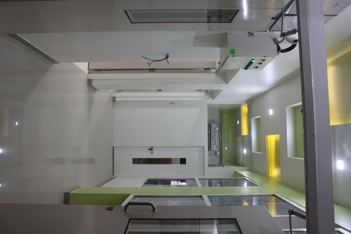 Service spine corridor between two modular operating bays at Insight Institute, with sterile transfer windows and accent green wall lighting